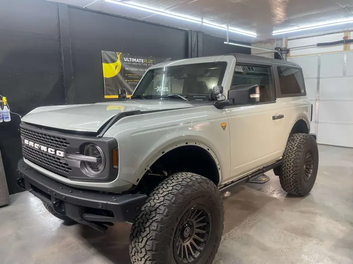 Cactus Gray Ford Bronco on mud-terrain tires in the install bay