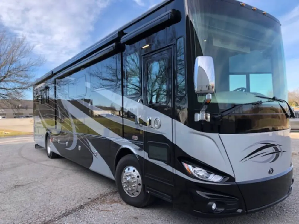 Black and silver Class A motorcoach parked in a lot after paint protection film on the front cap